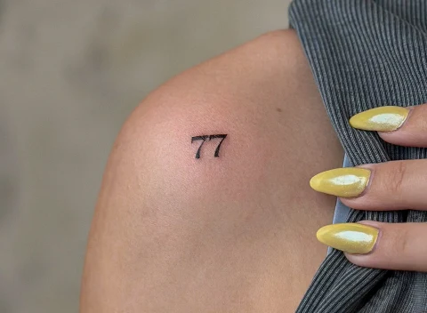 Kaligrafska tetovaža „77” na ramenu