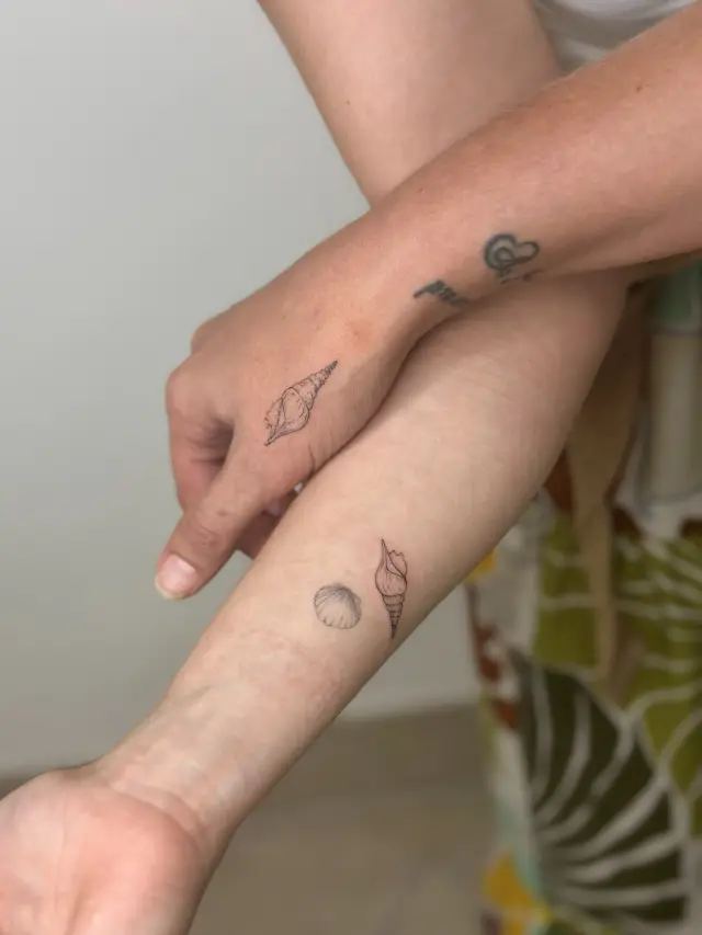 Fine line tetovaža školjke i kamenčića na podlaktici, freshly tattooed