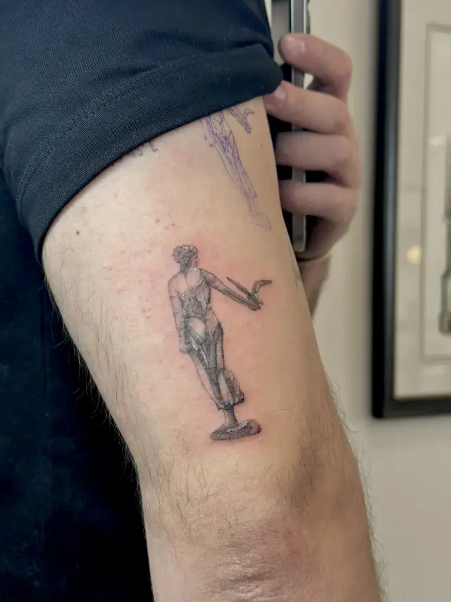 Fine line tetovaža figure klasičnog kipa na nadlaktici, freshly tattooed